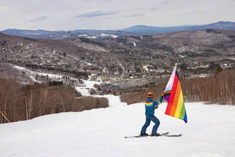 Joel holding pride flag top of trail looking at village