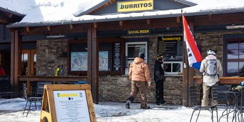 802 burrito menu sign with people in line blurred in the background