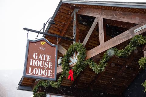 gate house lodge with holiday wreath hanging and snow falling