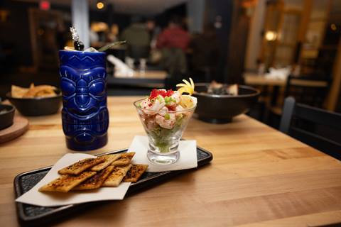 shrimp ceviche in a glass with crackers and a cocktail in a blue tiki mug