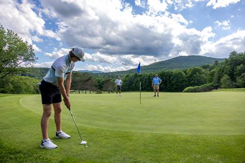 Golfer putting on a partly sunny day