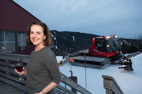 Women holding a glass of wine on the Allyns Lodge deck with a snowcat in the backround