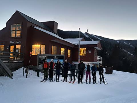Group of skiers standing outside of a ski lodge on a snowy mountain