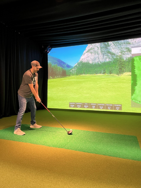 Person using a golf simulator about to swing the club