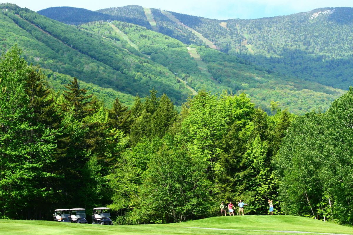 Golfers on the green with mountain behind them