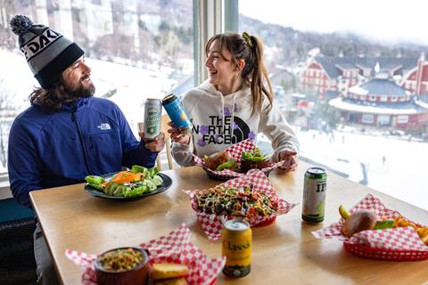 Two people sharing a drink at a table with plates of food