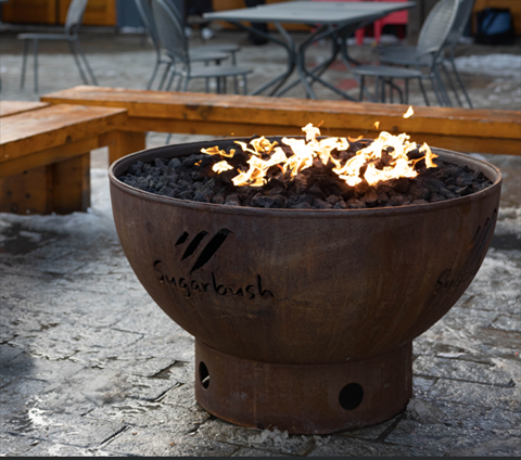 A lit fire pit outside of Castlerock Pub at Sugarbush Resort