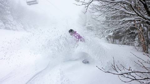 Snowboarder in a pink jacket on a powder day