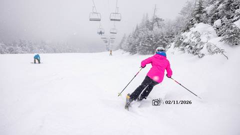 woman skier in pink jacket skiing with snow falling