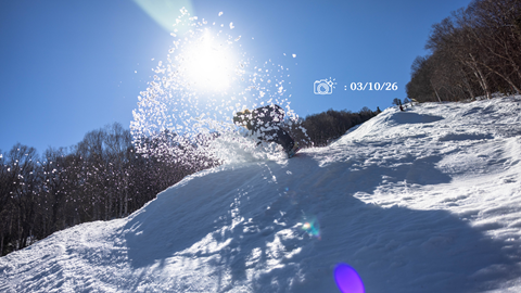 Snowboarder slashing slush in front of the sun