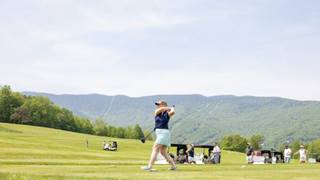 Woman teeing off golfing with Sugarbush in the background 